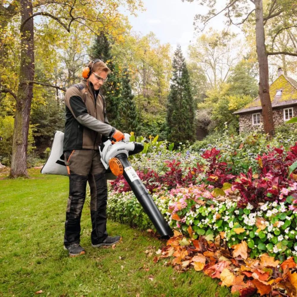 Souffleur de feuilles nettoyant un massif de fleurs en fin de saison